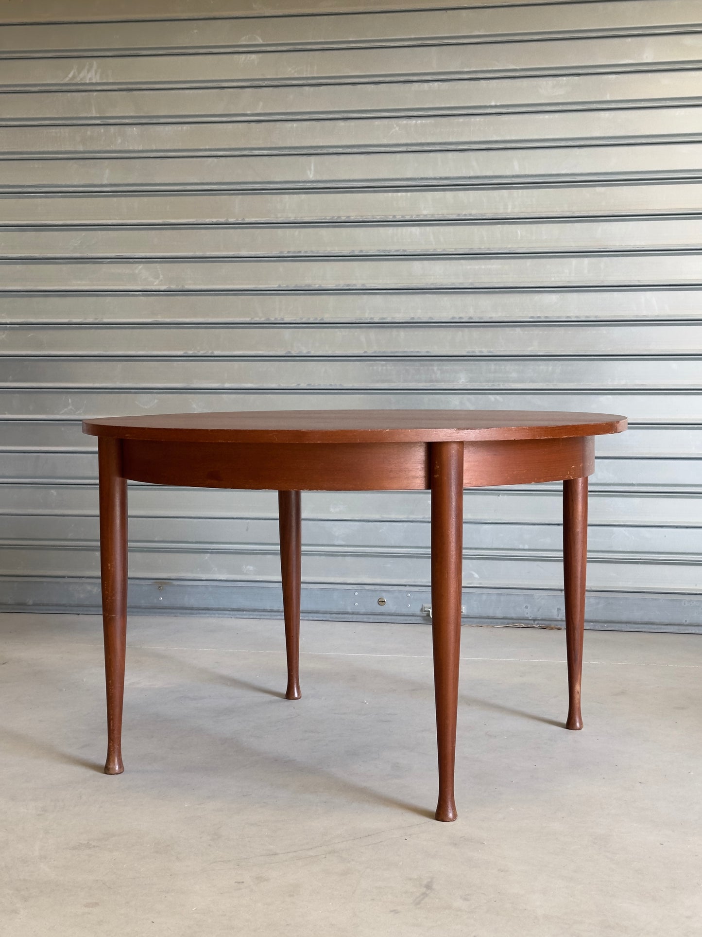 Table ronde vintage aux lignes épurées et au placage de teck chaleureux.