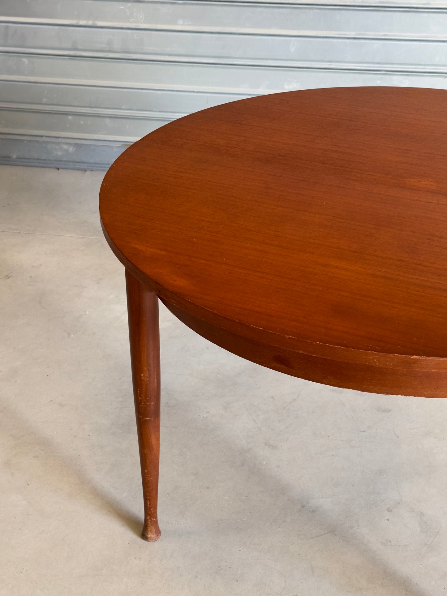 Table ronde vintage aux lignes épurées et au placage de teck chaleureux.
