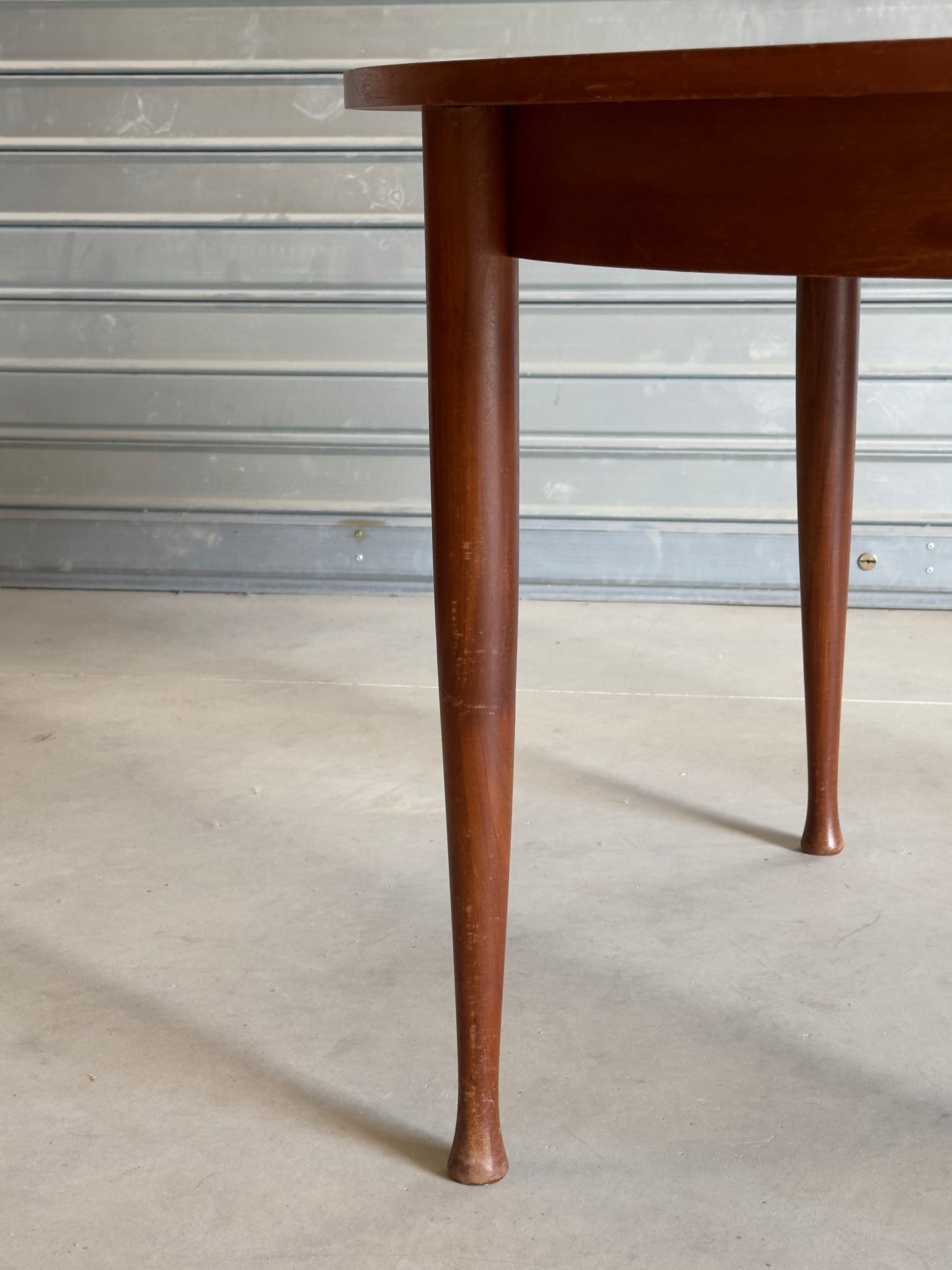 Table ronde vintage aux lignes épurées et au placage de teck chaleureux.