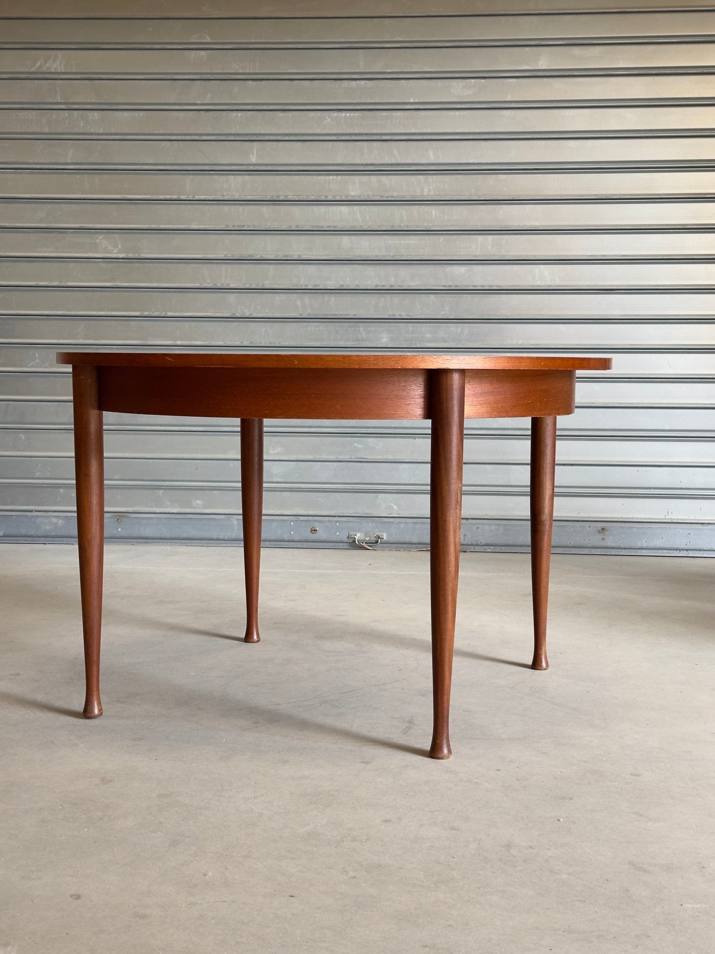 Table ronde vintage aux lignes épurées et au placage de teck chaleureux.