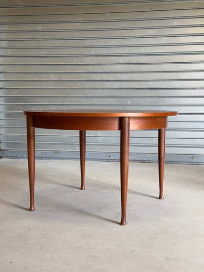 Table ronde vintage aux lignes épurées et au placage de teck chaleureux.