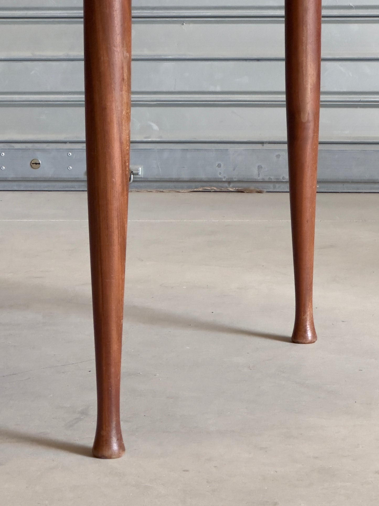 Table ronde vintage aux lignes épurées et au placage de teck chaleureux.