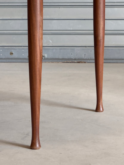 Table ronde vintage aux lignes épurées et au placage de teck chaleureux.