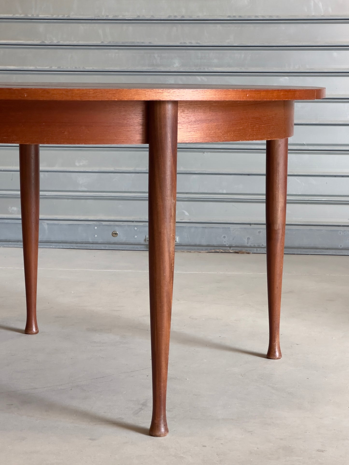 Table ronde vintage aux lignes épurées et au placage de teck chaleureux.