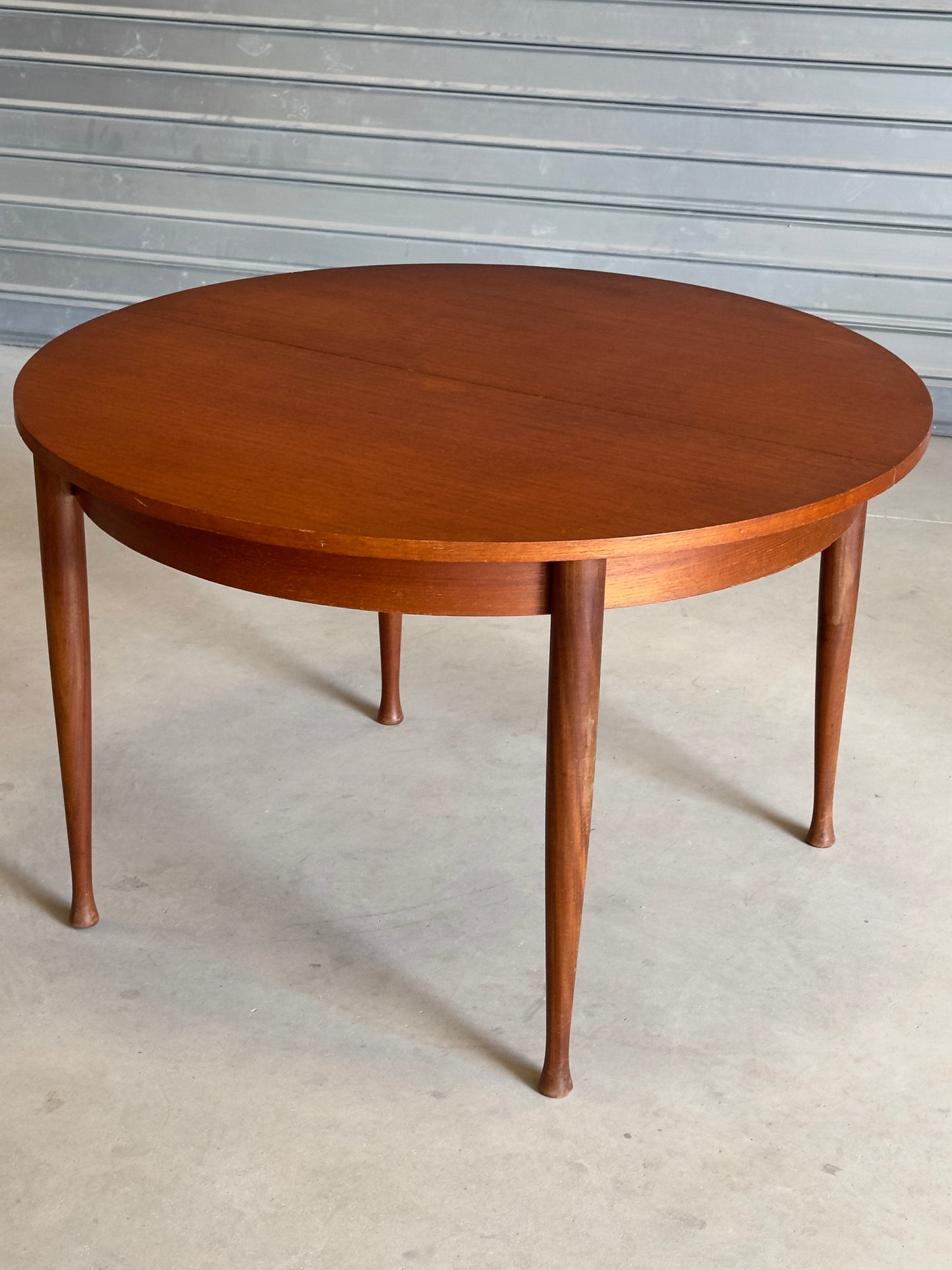 Table ronde vintage aux lignes épurées et au placage de teck chaleureux.