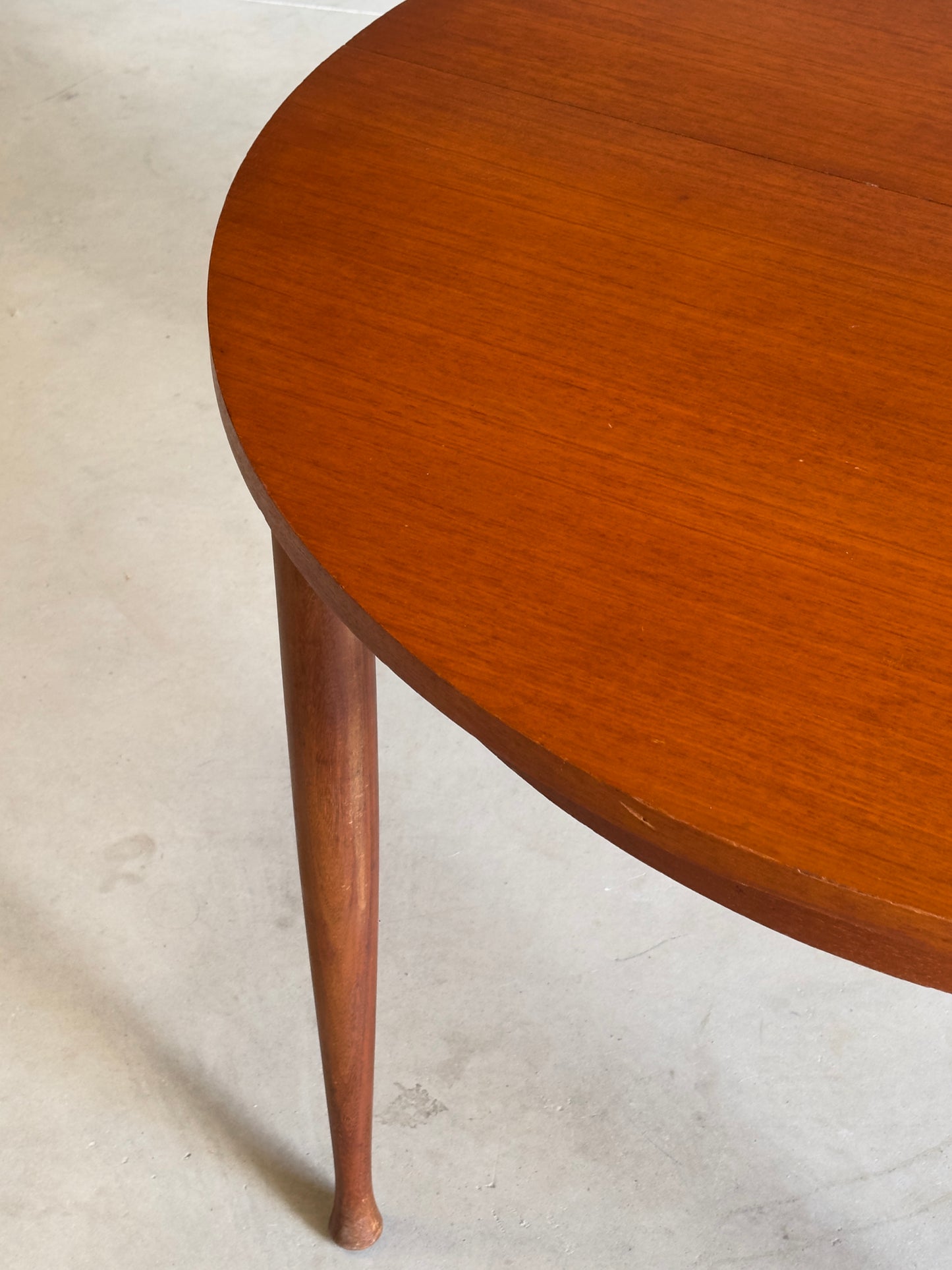Table ronde vintage aux lignes épurées et au placage de teck chaleureux.