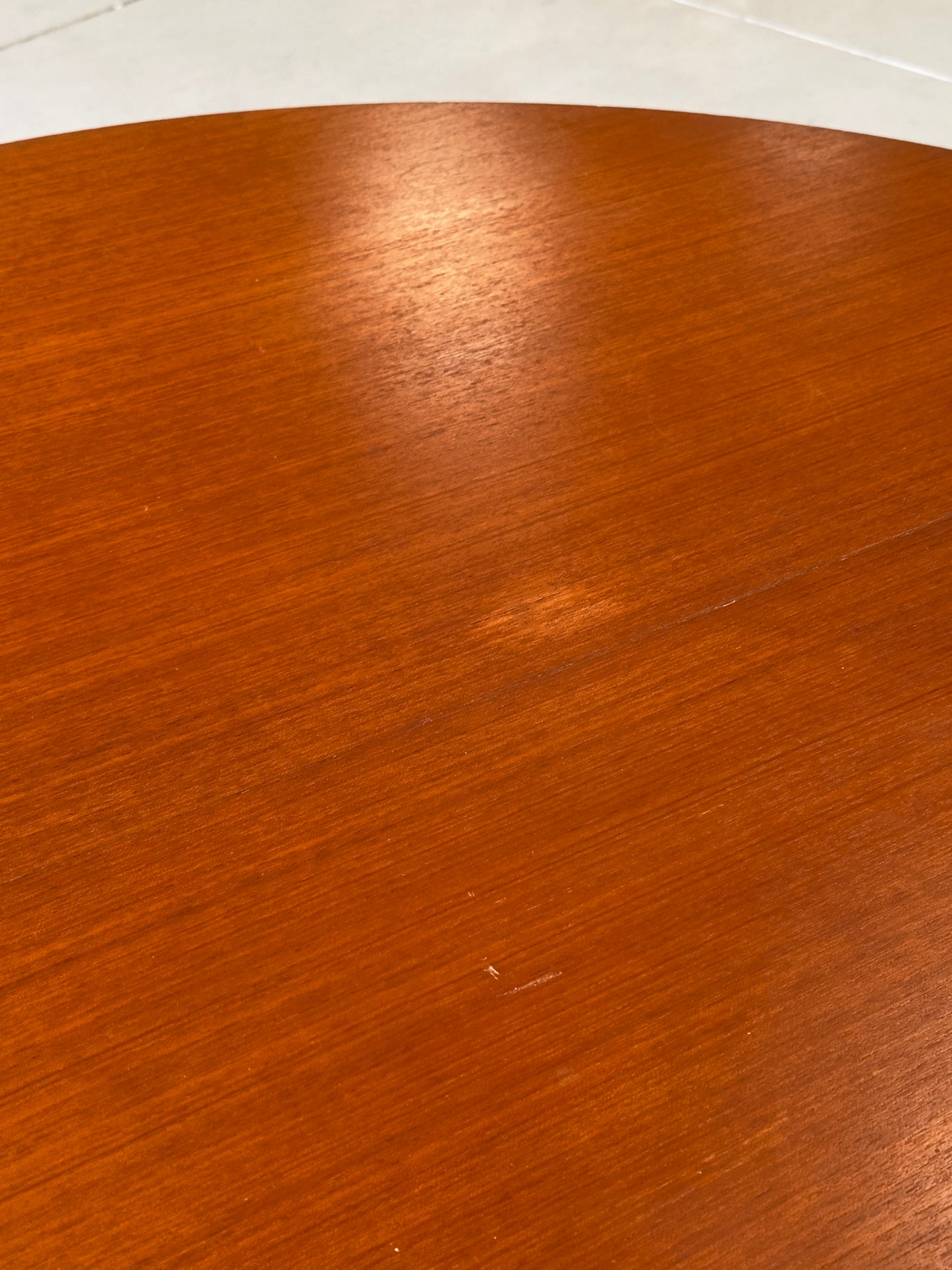 Table ronde vintage aux lignes épurées et au placage de teck chaleureux.