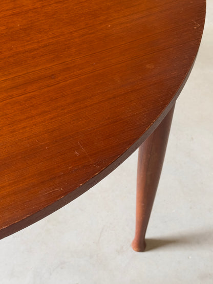 Table ronde vintage aux lignes épurées et au placage de teck chaleureux.