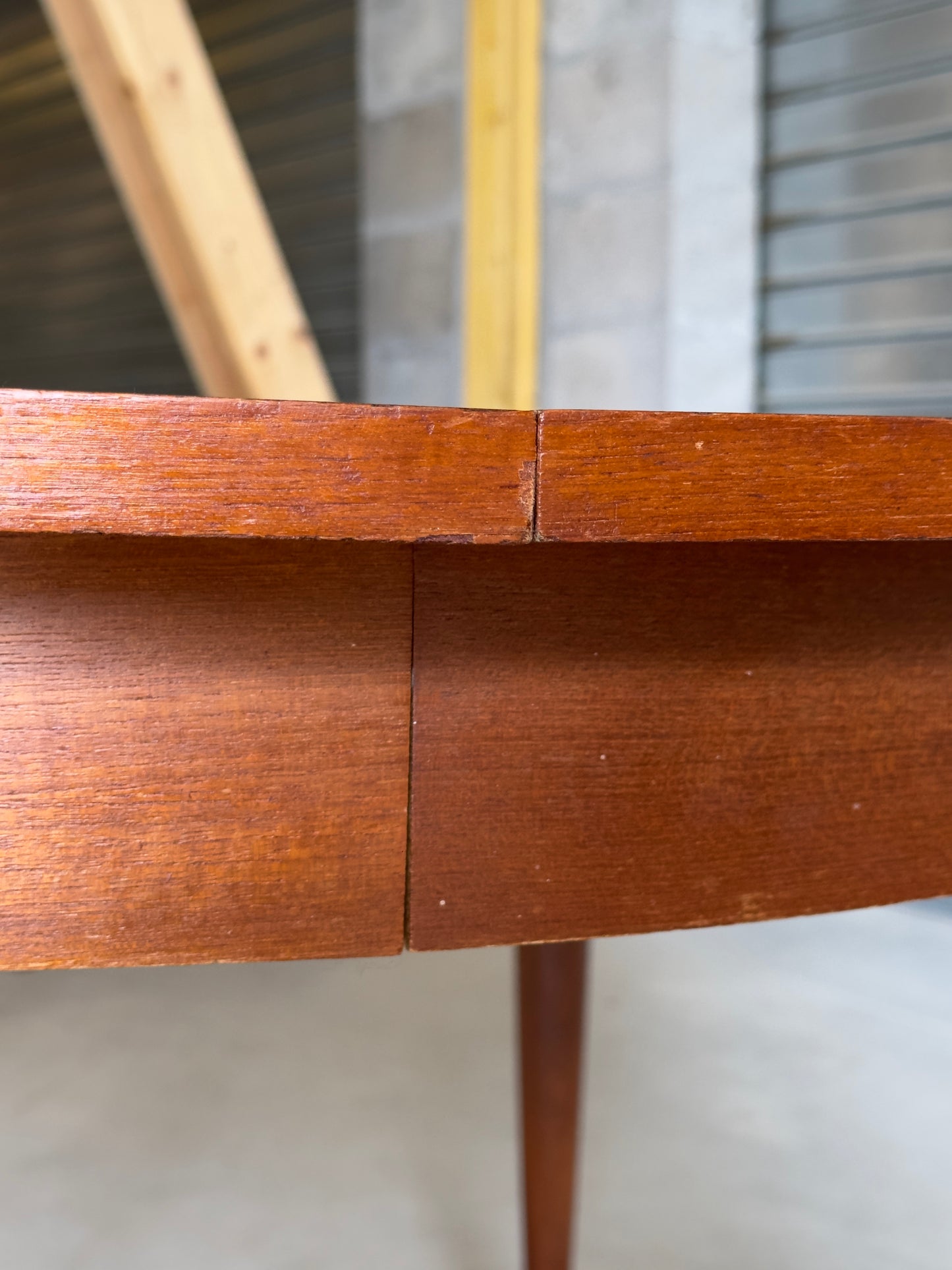 Table ronde vintage aux lignes épurées et au placage de teck chaleureux.