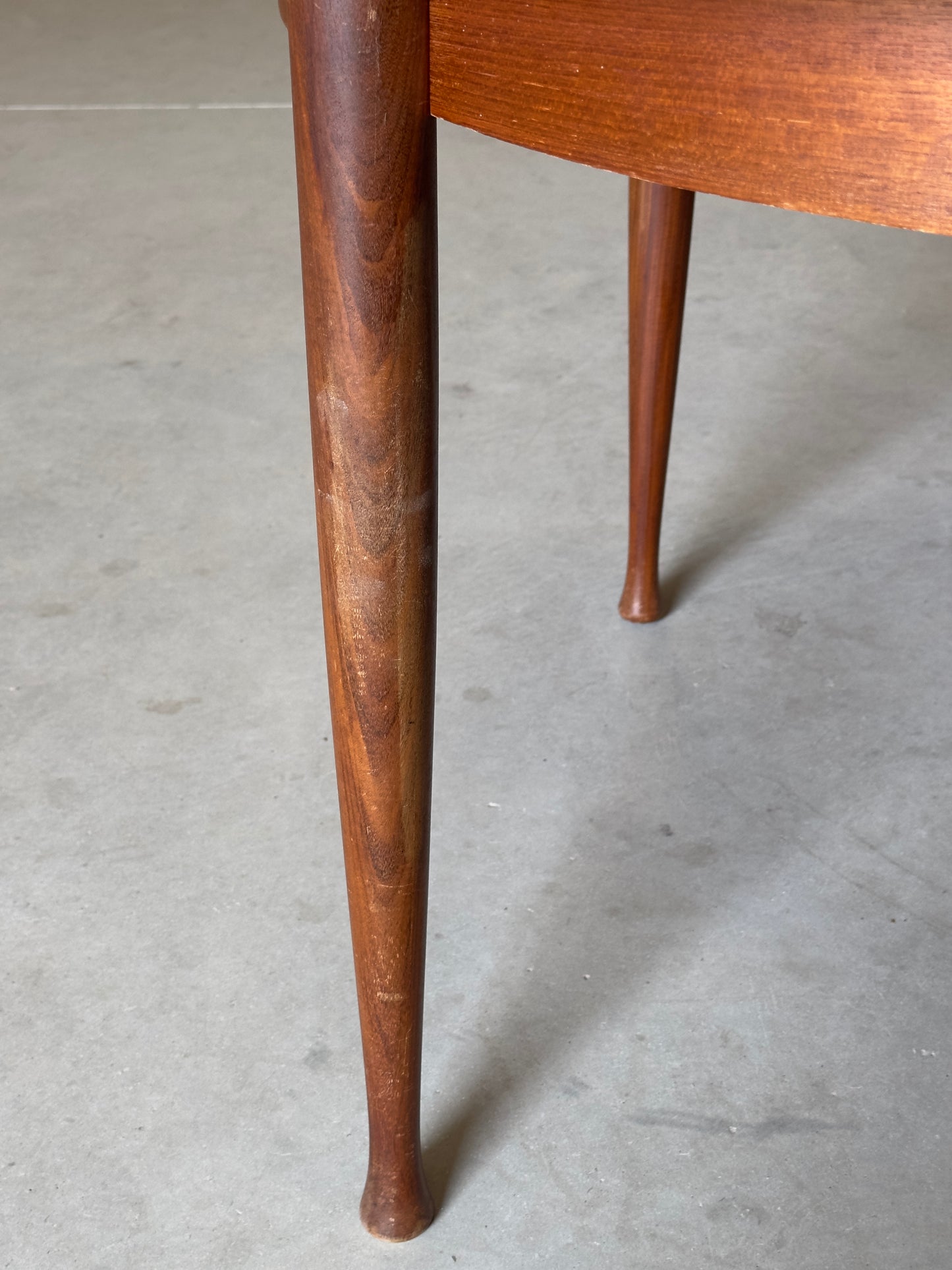 Table ronde vintage aux lignes épurées et au placage de teck chaleureux.