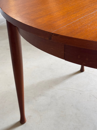 Table ronde vintage aux lignes épurées et au placage de teck chaleureux.