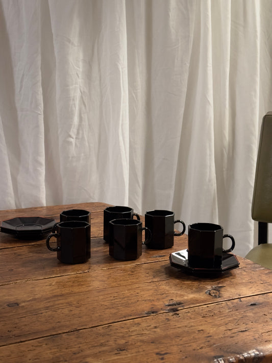 Un élégant service à café en céramique noire brillante, aux lignes facettées.