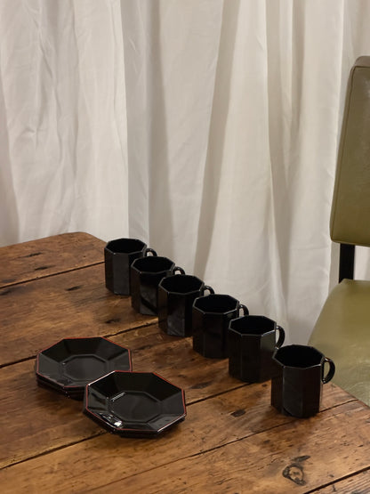 Un élégant service à café en céramique noire brillante, aux lignes facettées.