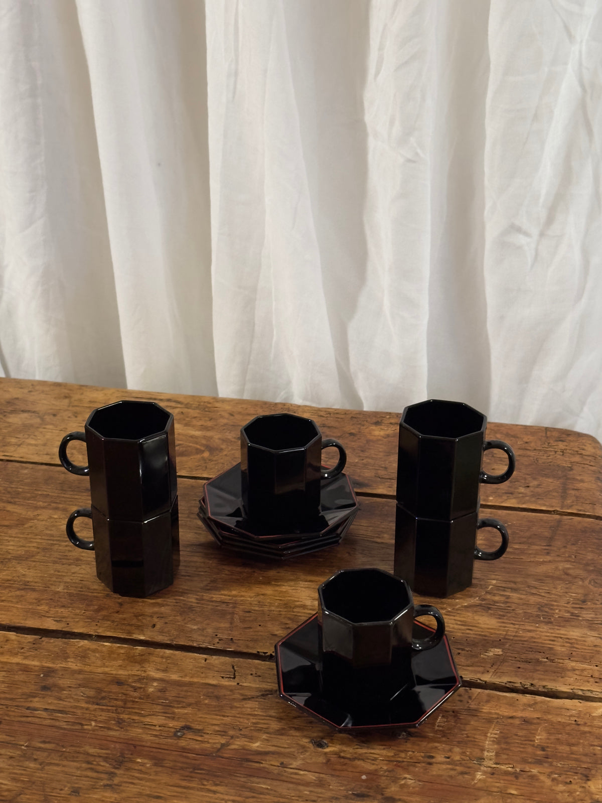 Un élégant service à café en céramique noire brillante, aux lignes facettées.