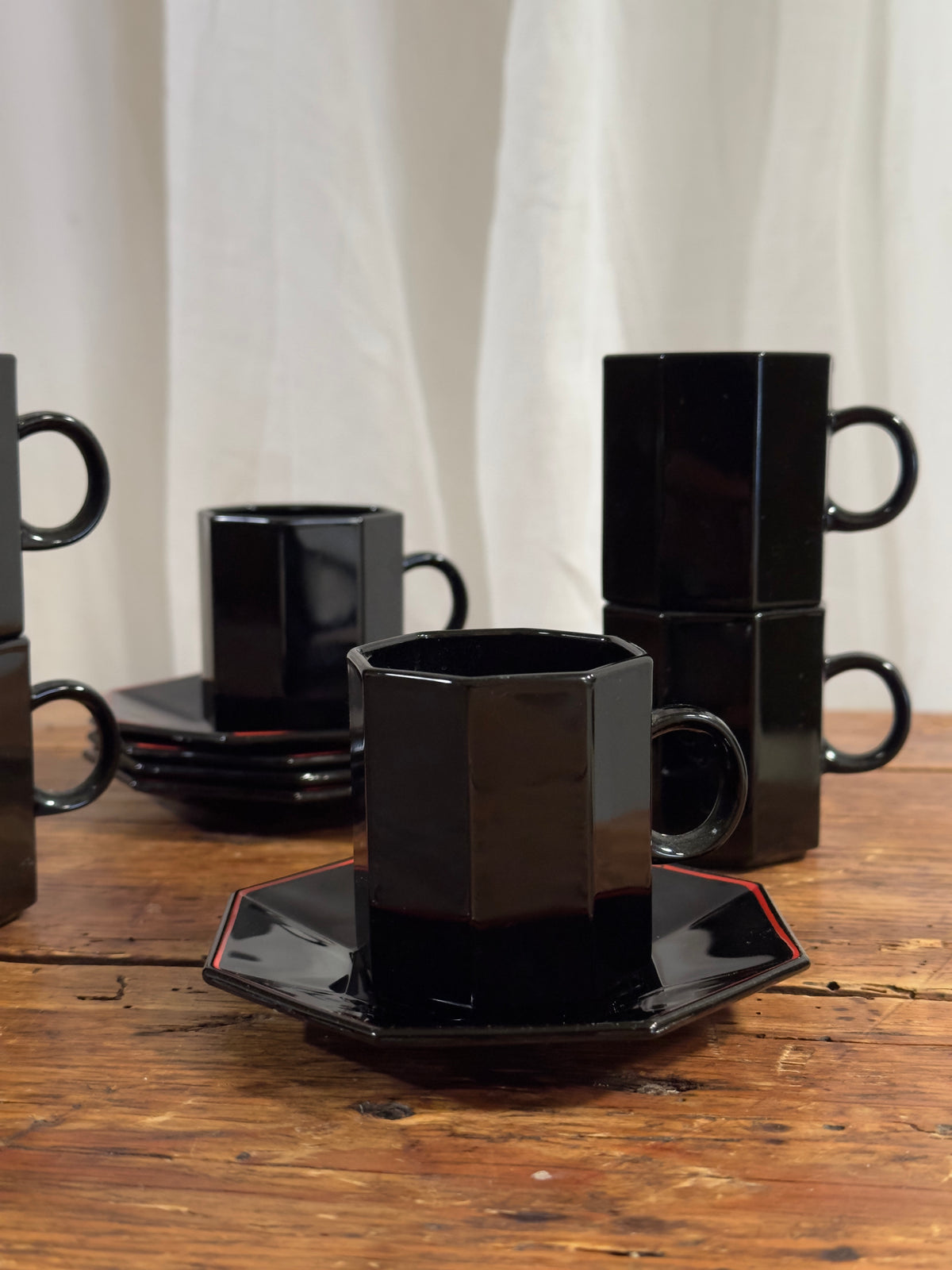 Un élégant service à café en céramique noire brillante, aux lignes facettées.