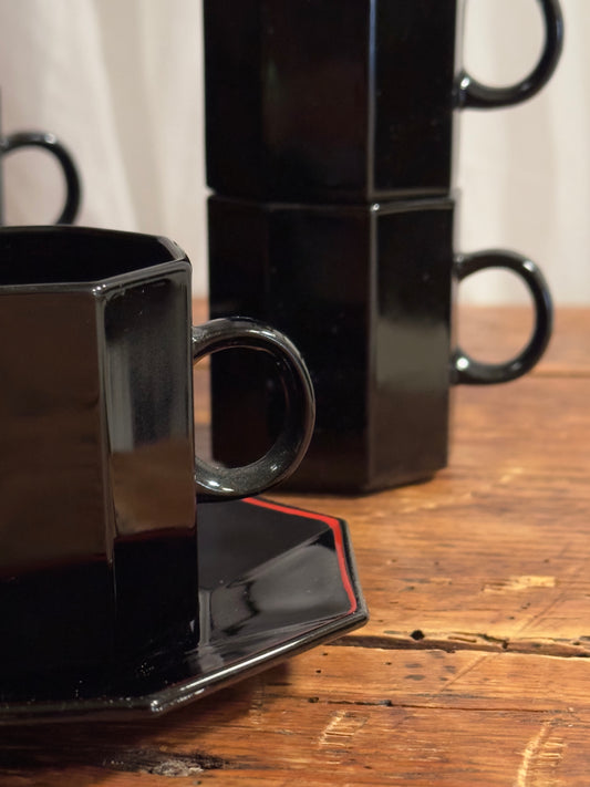 Un élégant service à café en céramique noire brillante, aux lignes facettées.